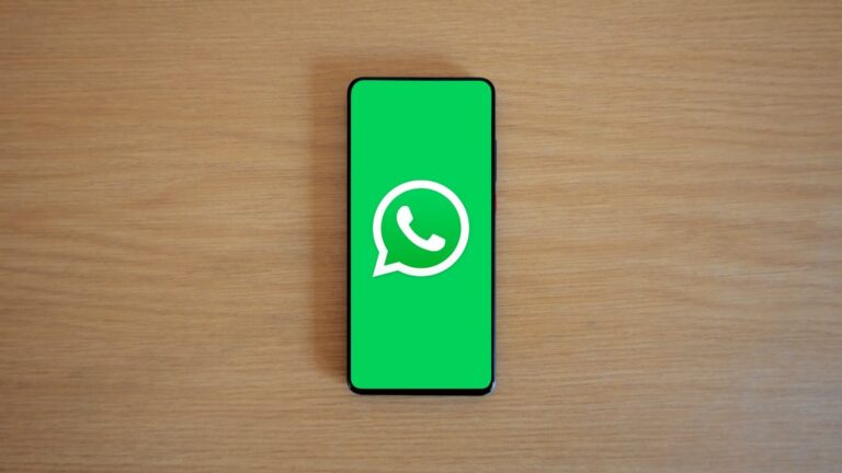 Top view of smartphone displaying WhatsApp logo on a wooden background, representing technology and communication.