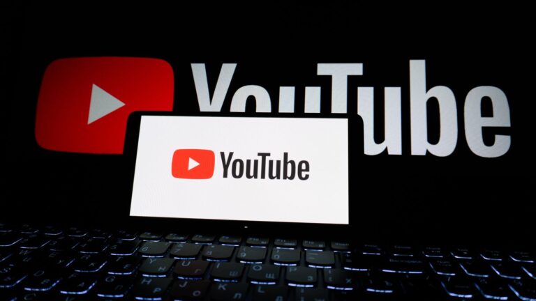 Close-up of YouTube logo displayed on a laptop screen in a dark environment.