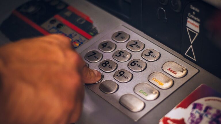 A hand pressing a button on an ATM keypad in Brasil, emphasizing digital banking.