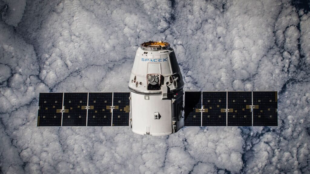 SpaceX Dragon spacecraft in orbit, highlighting advanced space technology with cloud backdrop.