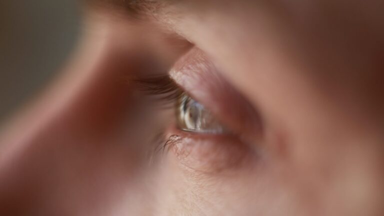 Closeup of crop anonymous sad person with teary eyes looking away thoughtfully on sunny day