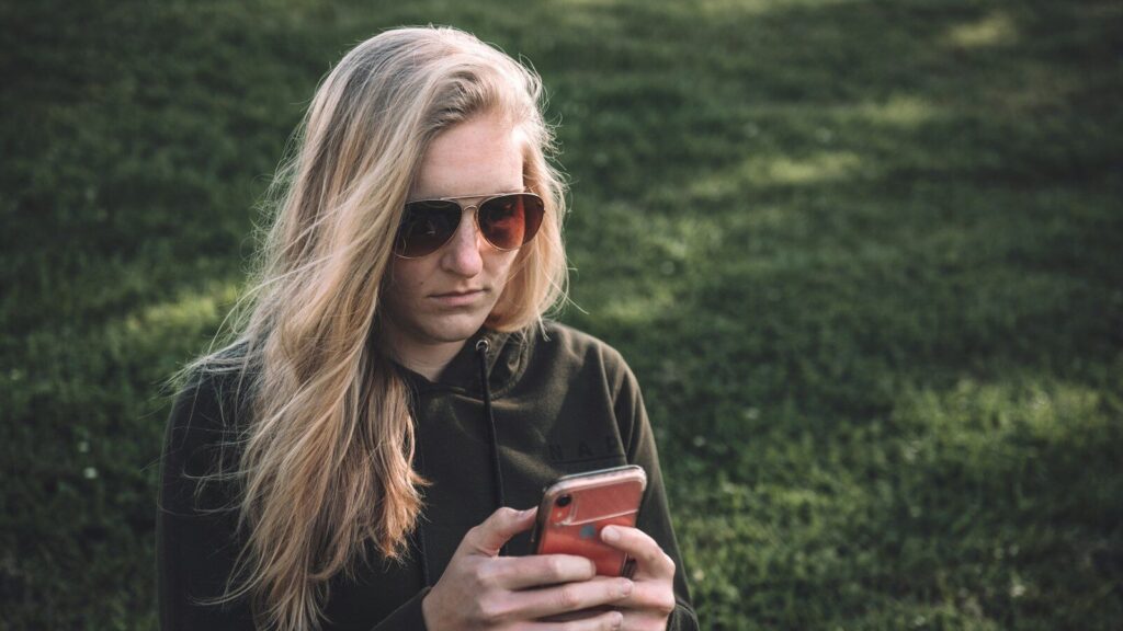 woman in black long sleeve shirt holding red smartphone