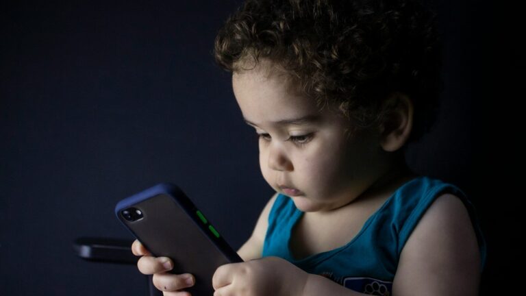 boy in blue tank top holding black iphone 5