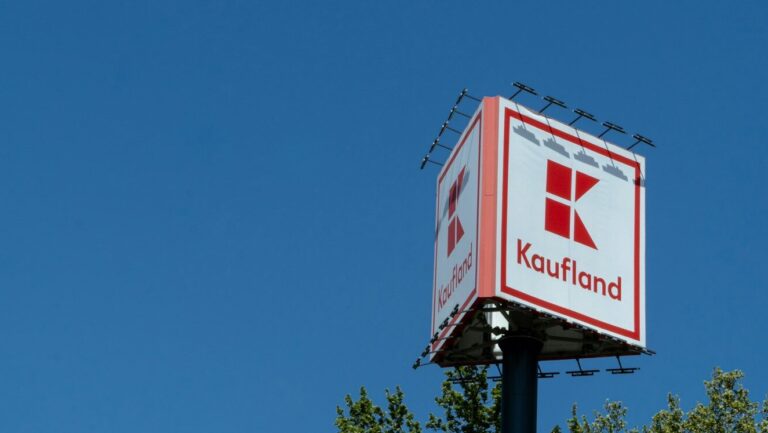 a red and white sign and some trees and a blue sky