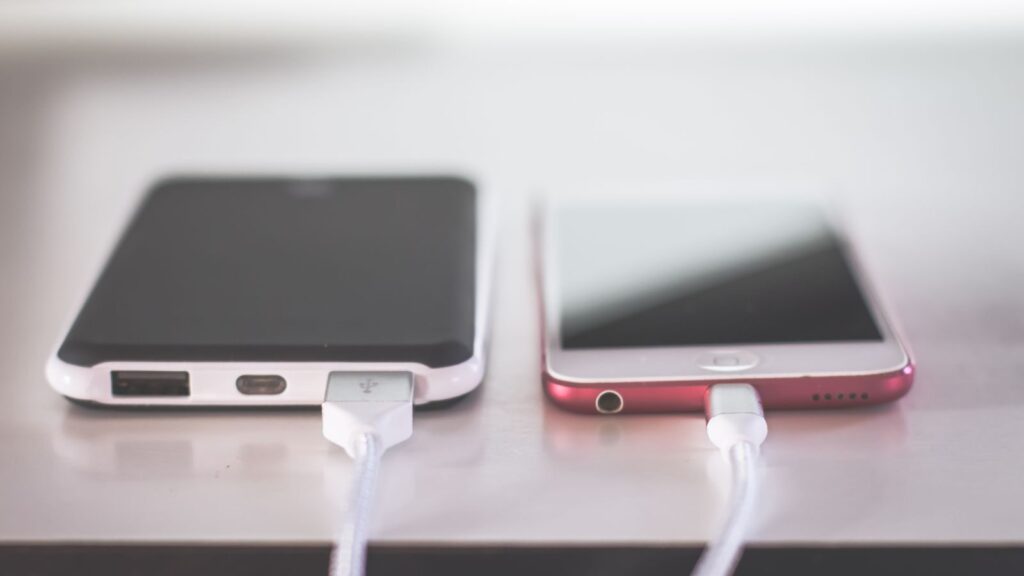 Two smartphones charging side by side on a desk. Modern and technological setting.