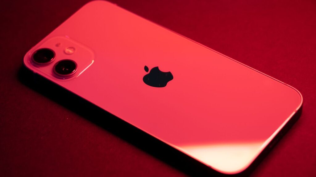 Close-up of a red smartphone with dual lenses on a red backdrop, highlighting sleek design and technology.