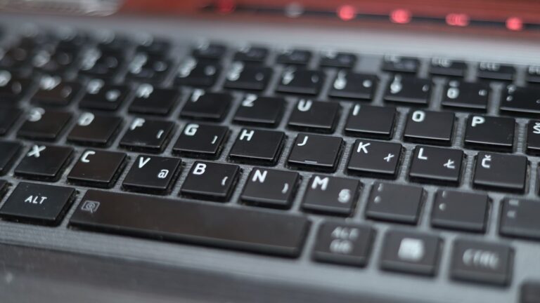Blurred close-up of a laptop keyboard with black keys and symbols, highlighting technology.