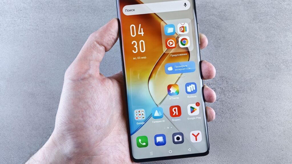 Close-up of a hand holding a smartphone displaying apps on the screen against a textured background.
