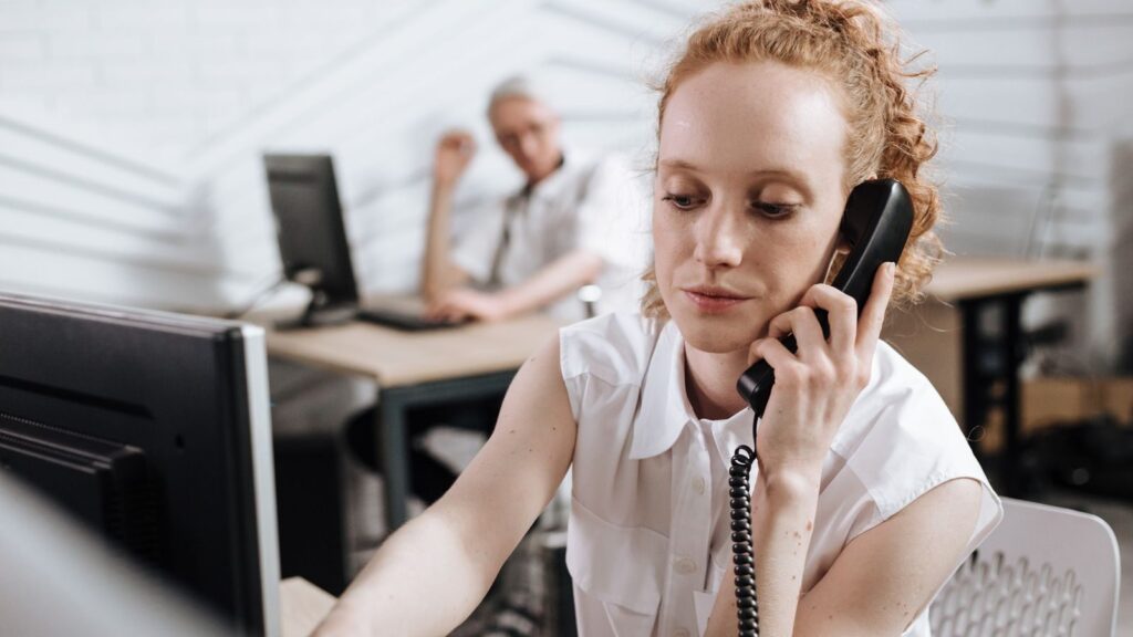 Focused businesswoman making phone call at her desk in a modern office.
