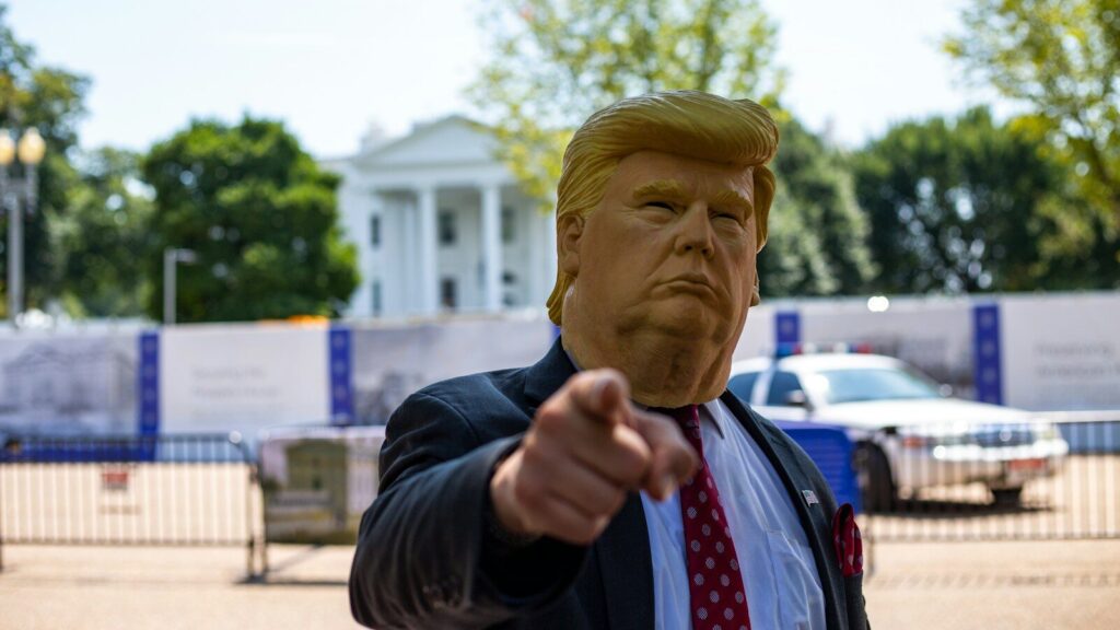 man wearing Donald Trump mask standing in front of White House