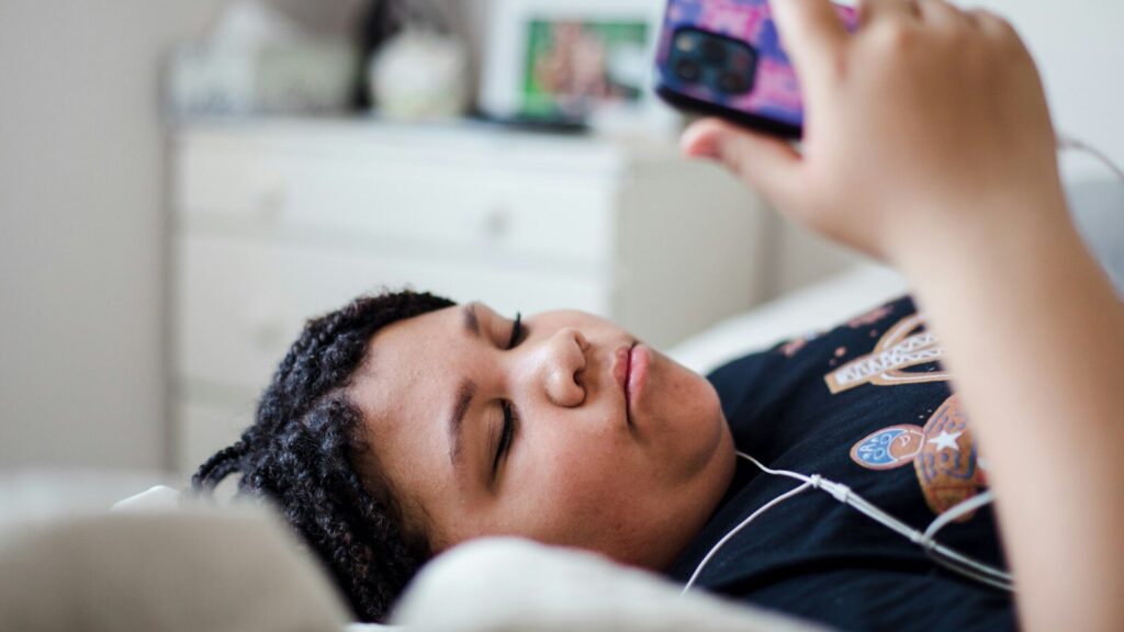 a person laying in bed with a cell phone