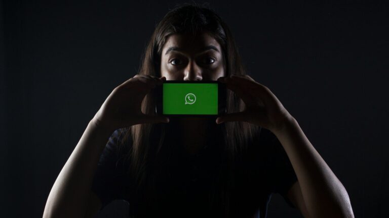 woman holding black smartphone at Whatsapp logo