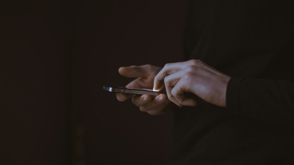 silhouette photo of person holding smartphone