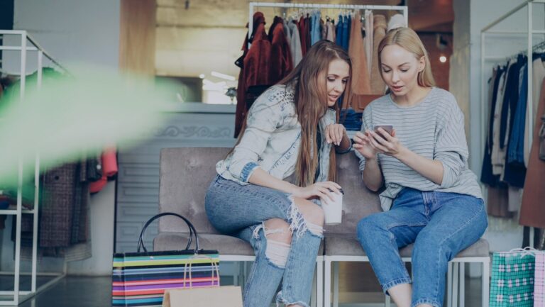 Two women are looking at a phone in a store