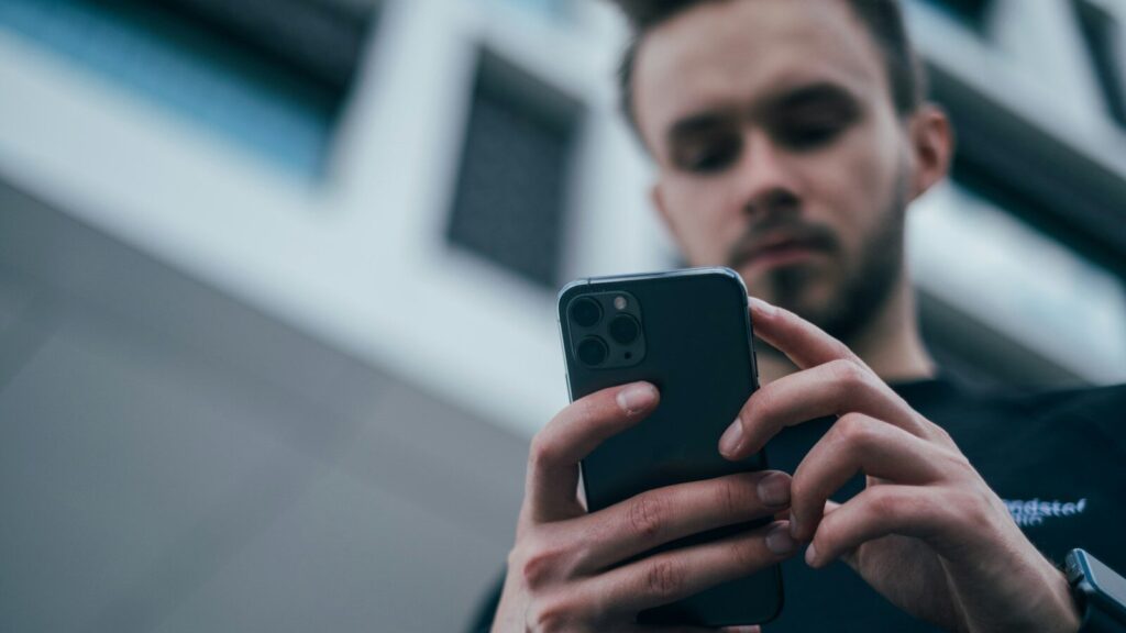 man wearing black sweater using smartphone