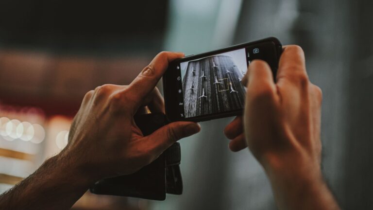 Hands holding a smartphone capturing an indoor scene in Dubai, featuring a modern lifestyle.