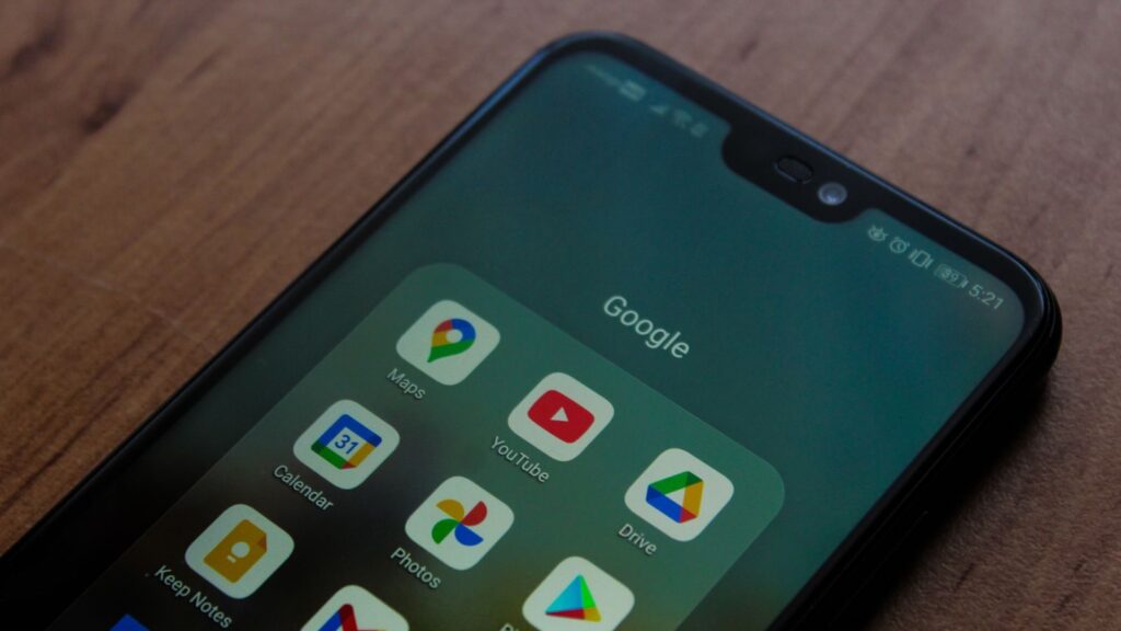 Close-up of a smartphone showing various Google apps on its screen.