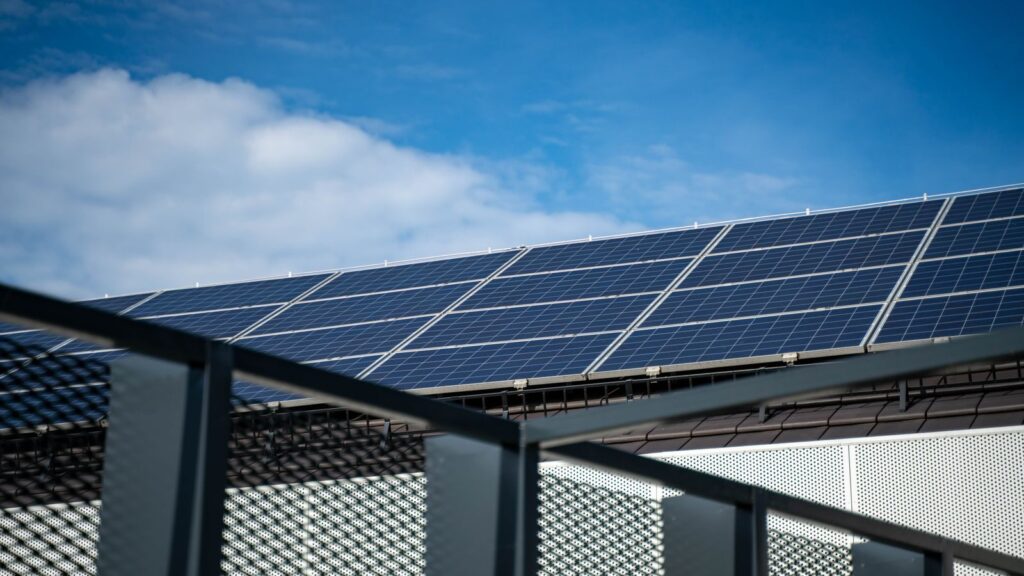 Close-up view of modern solar panels on a rooftop against a clear blue sky, representing clean energy.