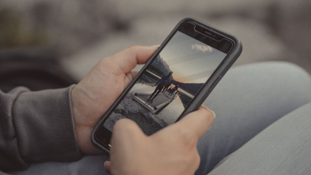 Close-up of hands holding a smartphone showing a mountain scene, captured outdoors in Banff.