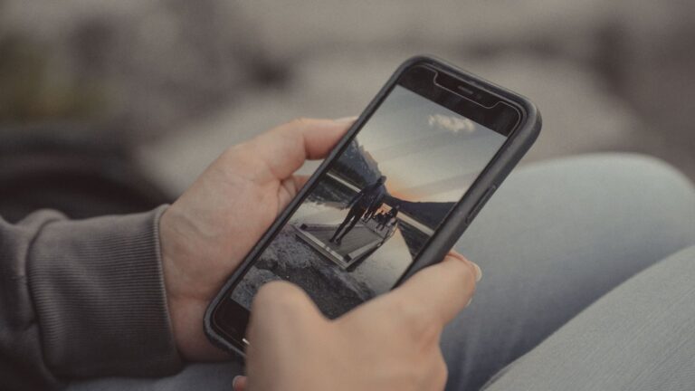 Close-up of hands holding a smartphone showing a mountain scene, captured outdoors in Banff.