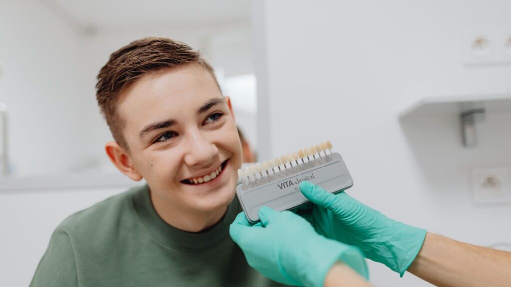 A teenager smiling during a dental shade matching procedure at a dentist office.