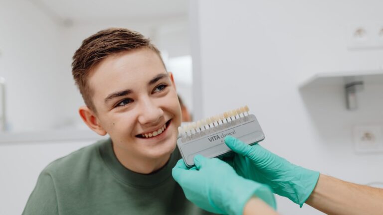 A teenager smiling during a dental shade matching procedure at a dentist office.