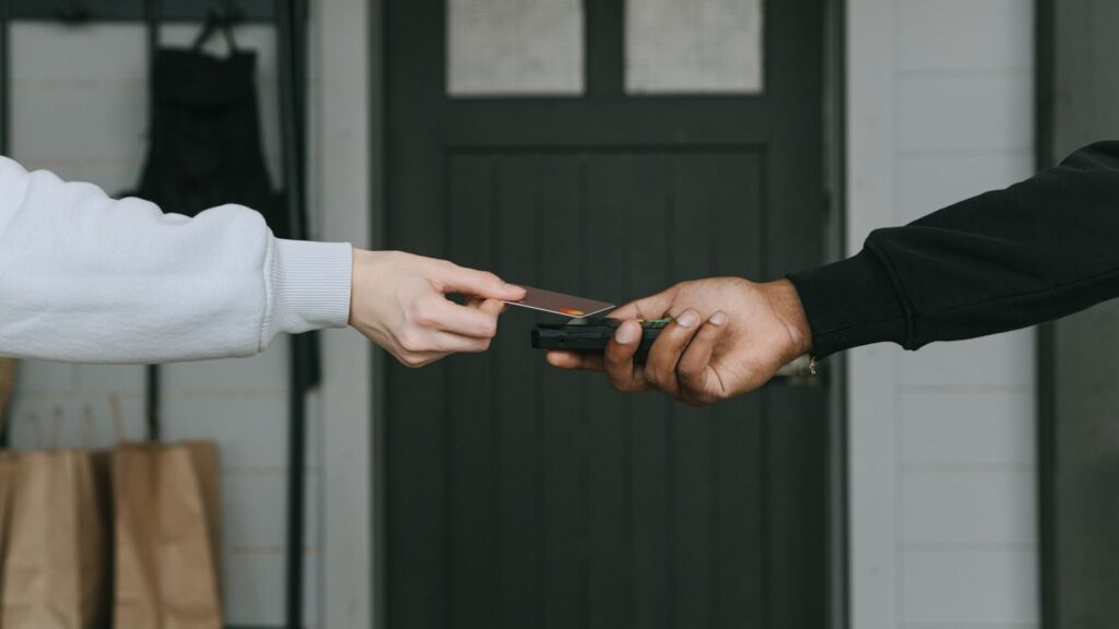 Close-up of hands making a contactless card payment indoors, highlighting cashless transaction technology.