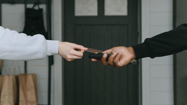 Close-up of hands making a contactless card payment indoors, highlighting cashless transaction technology.