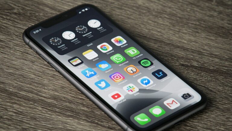 A smartphone with a home screen full of app icons on a wooden surface