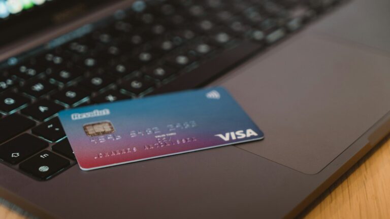 A blue and red gradient debit card resting on a dark laptop keyboard