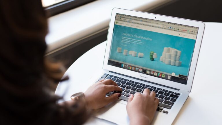 Businesswoman working on laptop with Android 6.0 Marshmallow webpage open.