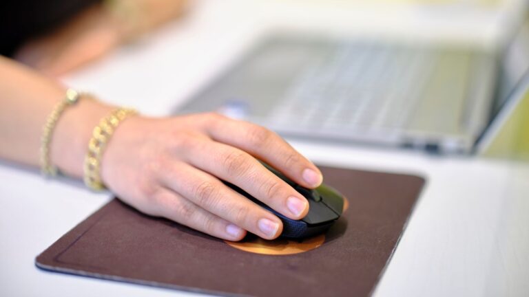 A person using a wireless mouse at a desk, perfect for business or technology themes.