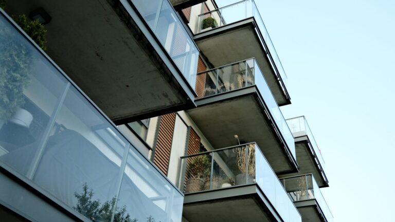 A modern residential building's glass balconies under a clear sky, showcasing contemporary architecture.