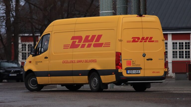 Yellow DHL van on street showing company branding and delivery services.