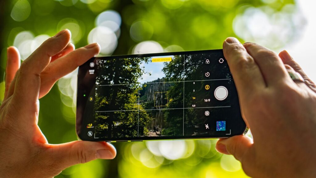 Hands holding smartphone capturing scenic view of nature in Germany outdoors.