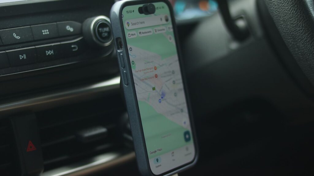 A smartphone with a map app displayed inside a car, showing modern navigation.