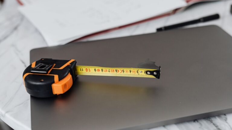 Close-up image of a measuring tape and a laptop on a work desk, representing precision in work.