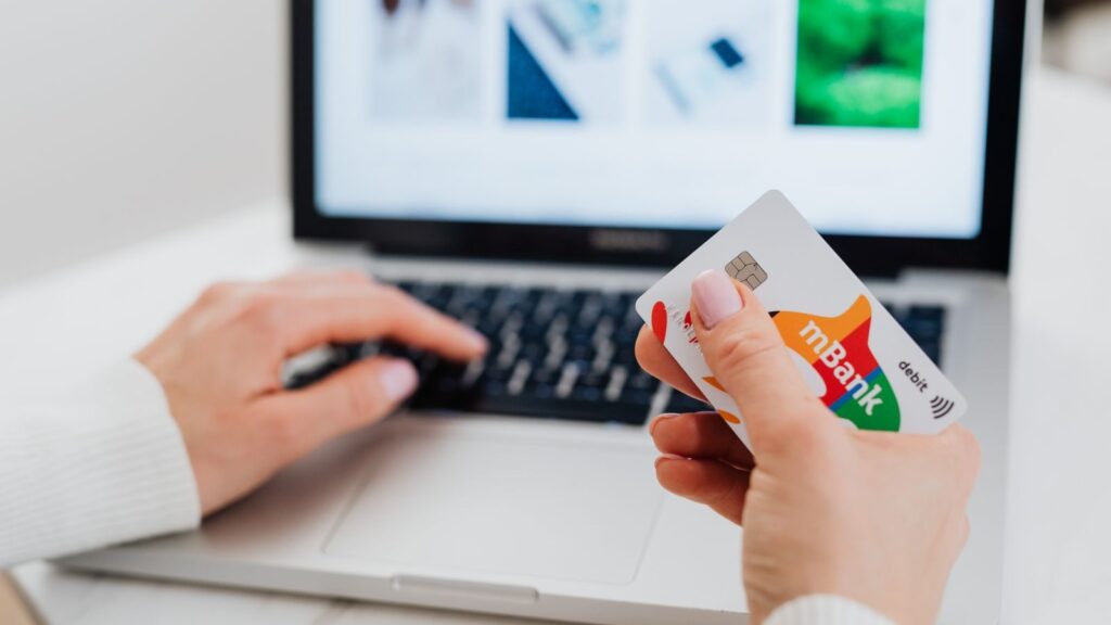 Close-up of hands using a laptop and holding a credit card for an online transaction.