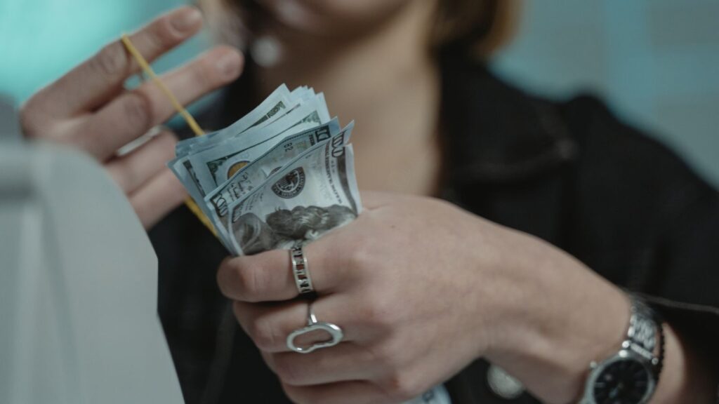 Close-up of a person counting US dollar bills indoors, focusing on finance and money handling.