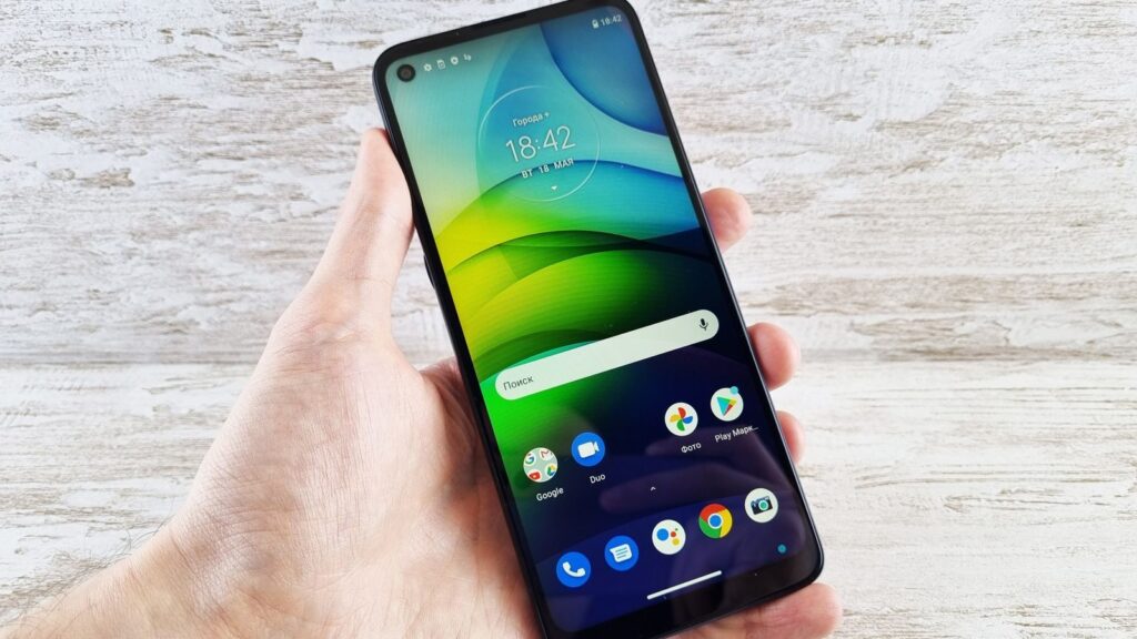 Close-up of a hand holding a smartphone with vibrant screen indoors, bright and clear display.