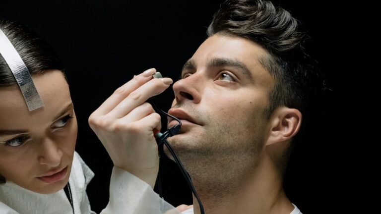 Close-up of a man receiving an eye check-up from a female scientist using an advanced device.