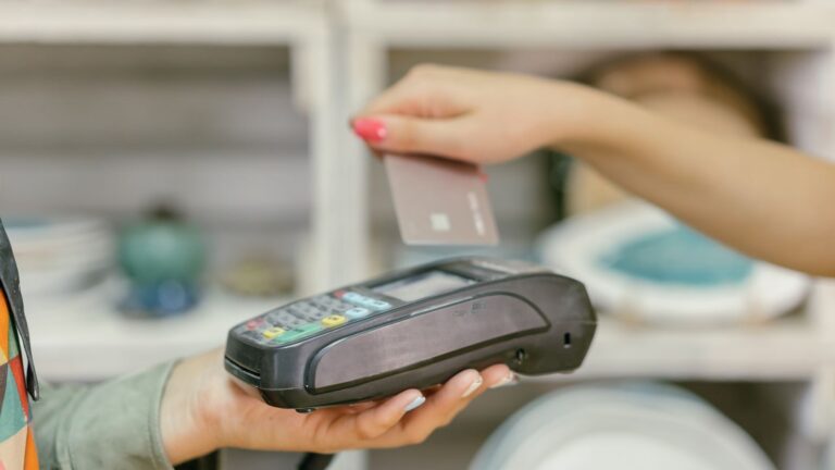 A hand using a credit card for payment at a point of sale terminal, close-up view.