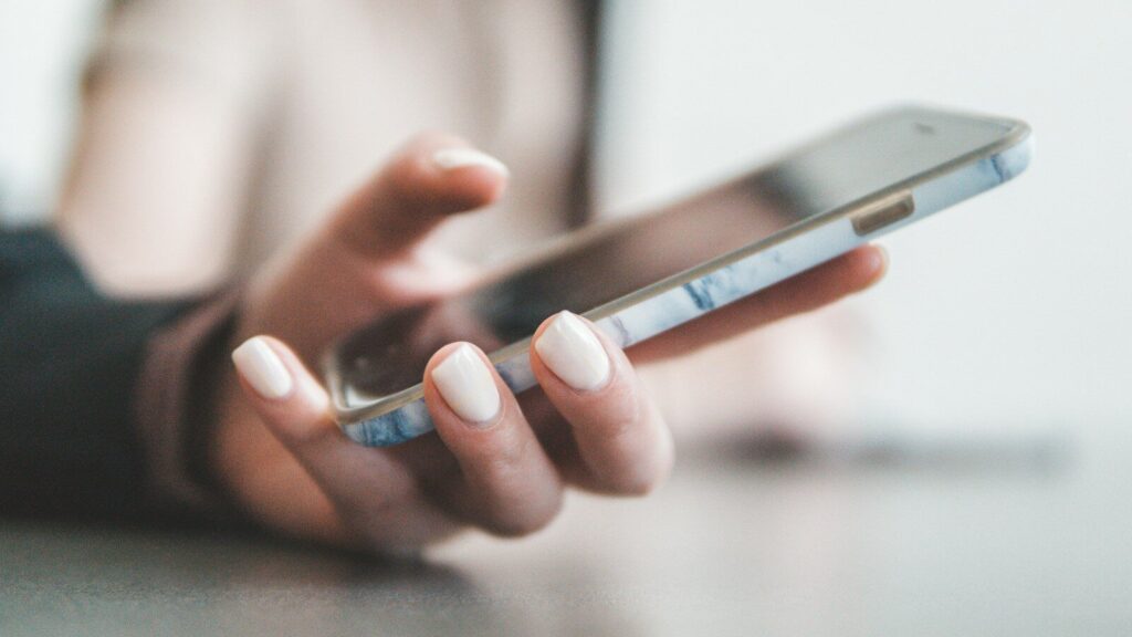 A person holding a smartphone with a marble pattern case in a bright room