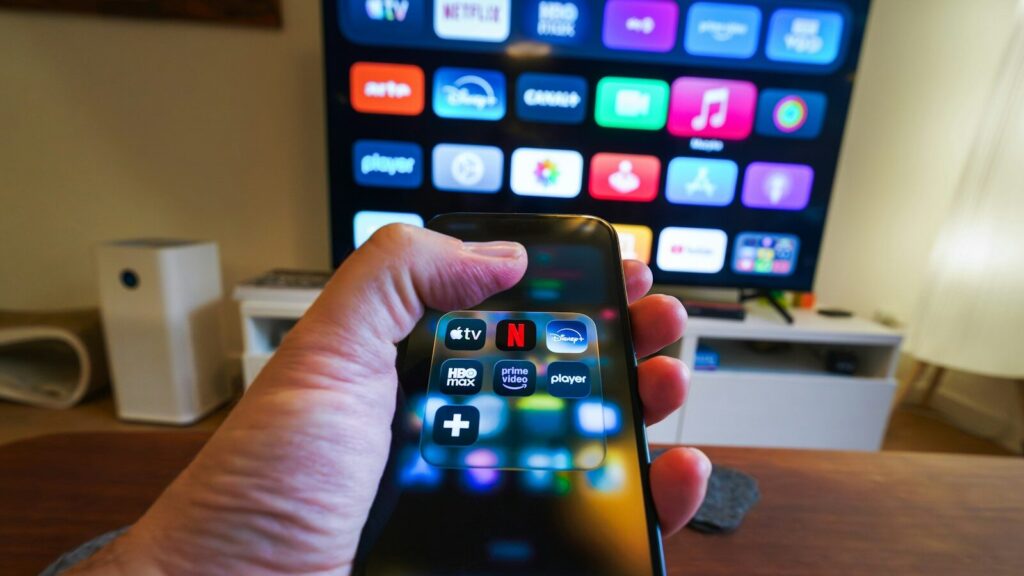 Hand holding smartphone controlling smart TV apps