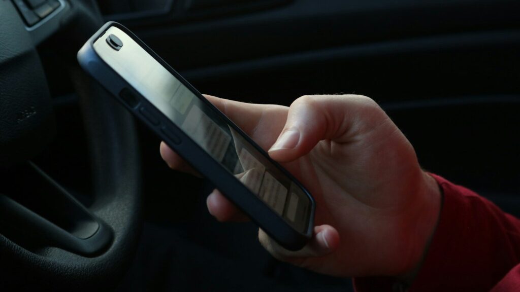 Hand holding a smartphone inside a car