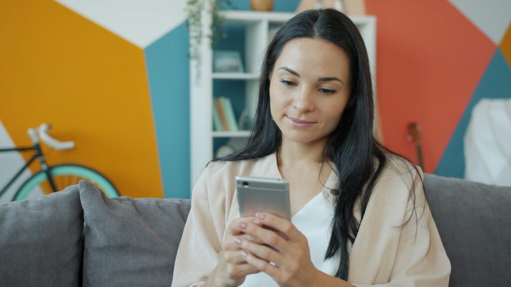 A woman looking at her smartphone on a couch