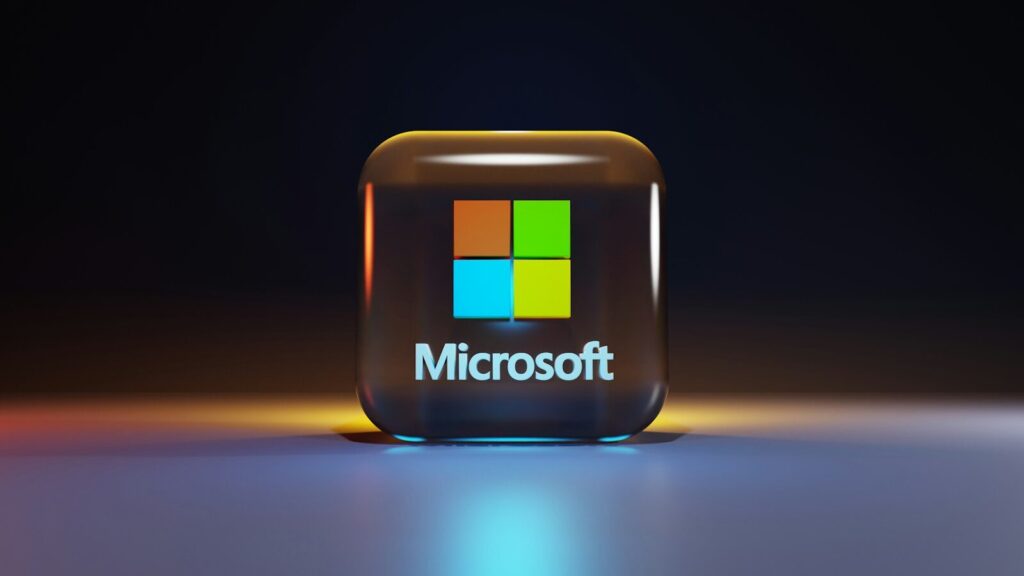 A glossy glass cube with the Microsoft logo on a dark surface
