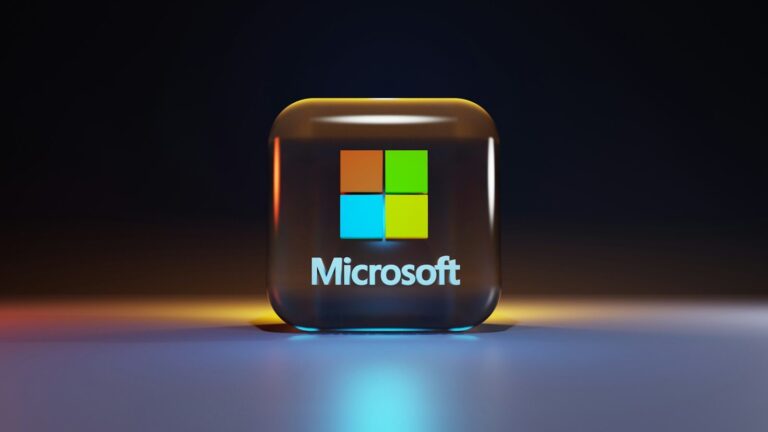 A glossy glass cube with the Microsoft logo on a dark surface