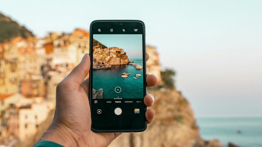 person holding a phone near cliff during daytime
